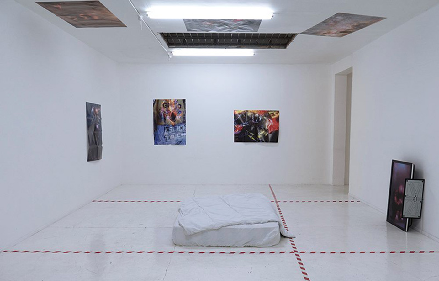 A bare, tiled room, with a poster of a motorcycle crash on each wall